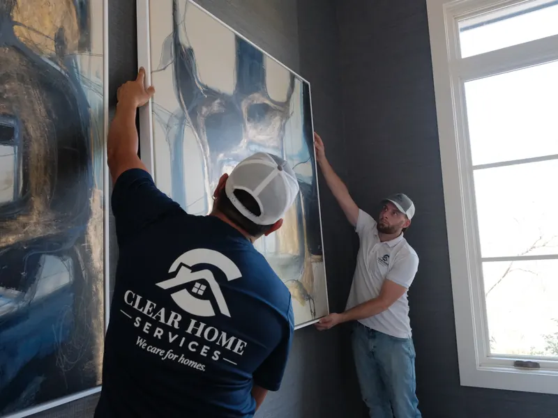 Two Clear Home Services technicians hanging a large abstract painting