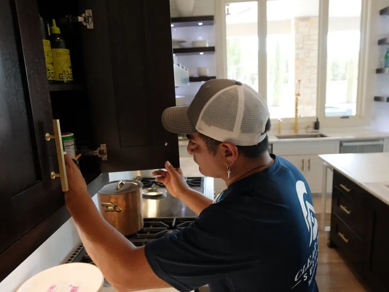 Technician adjusting a kitchen cabinet door hinge
