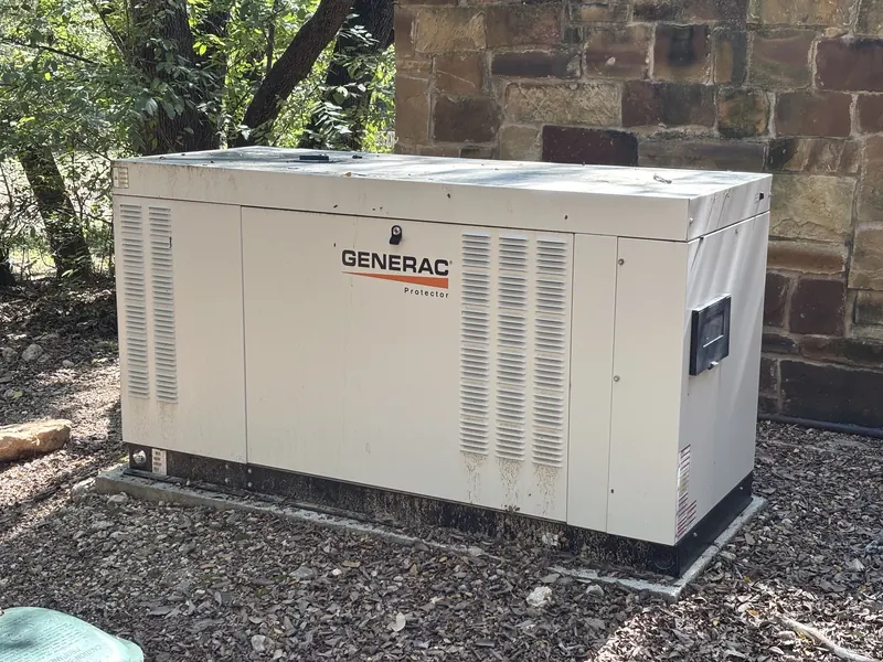 Home standby generator installed beside a stone wall