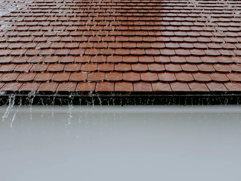 Rain running off a tiled roof edge into a gutter