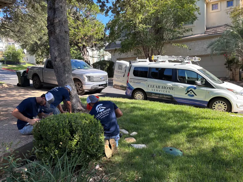Three Clear Home Services technicians working on a front-yard irrigation system beside the branded CHS van
