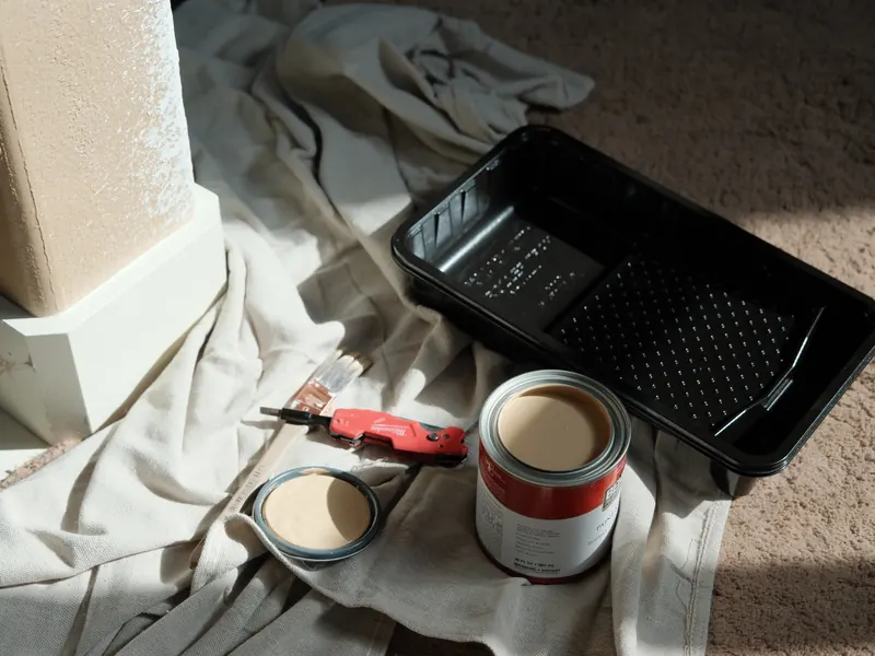 Paint can, roller tray, and drop cloth laid out for touch-up painting