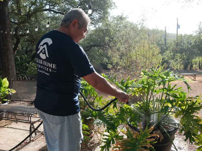Clear Home Services technician watering potted patio plants