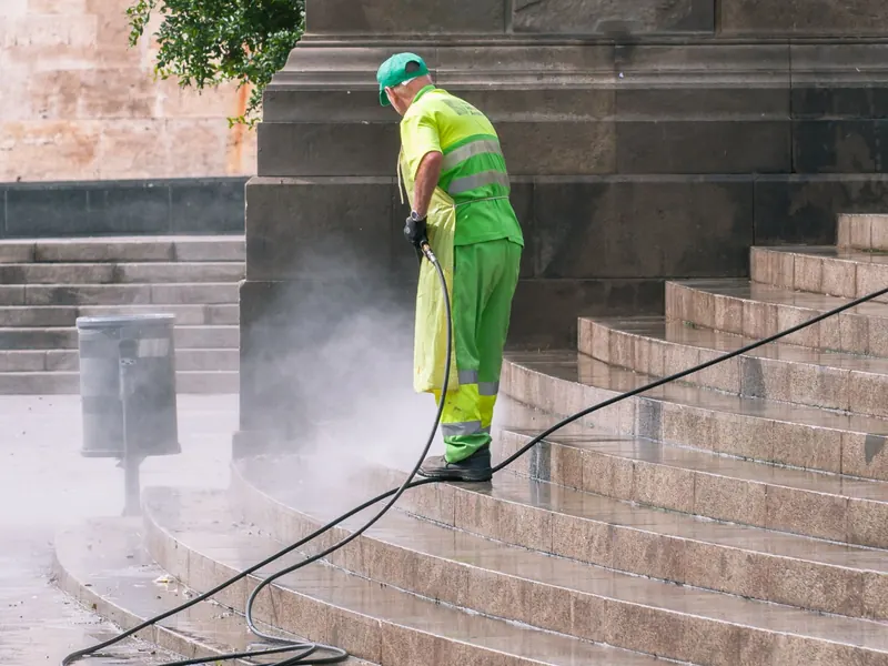 Worker pressure washing a set of stone steps