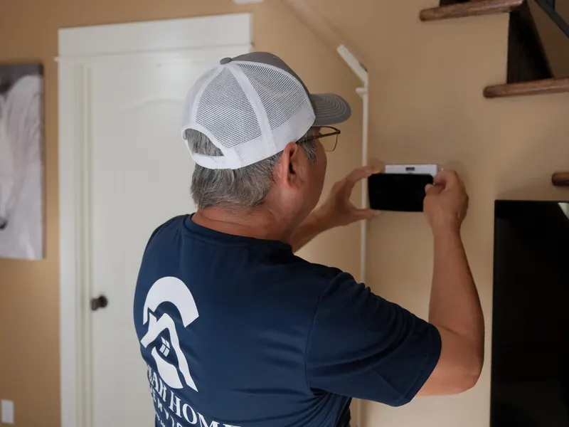 Technician installing a smart thermostat on an interior wall