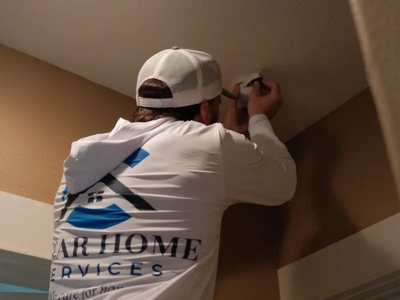 Clear Home Services technician servicing a ceiling-mounted smoke detector